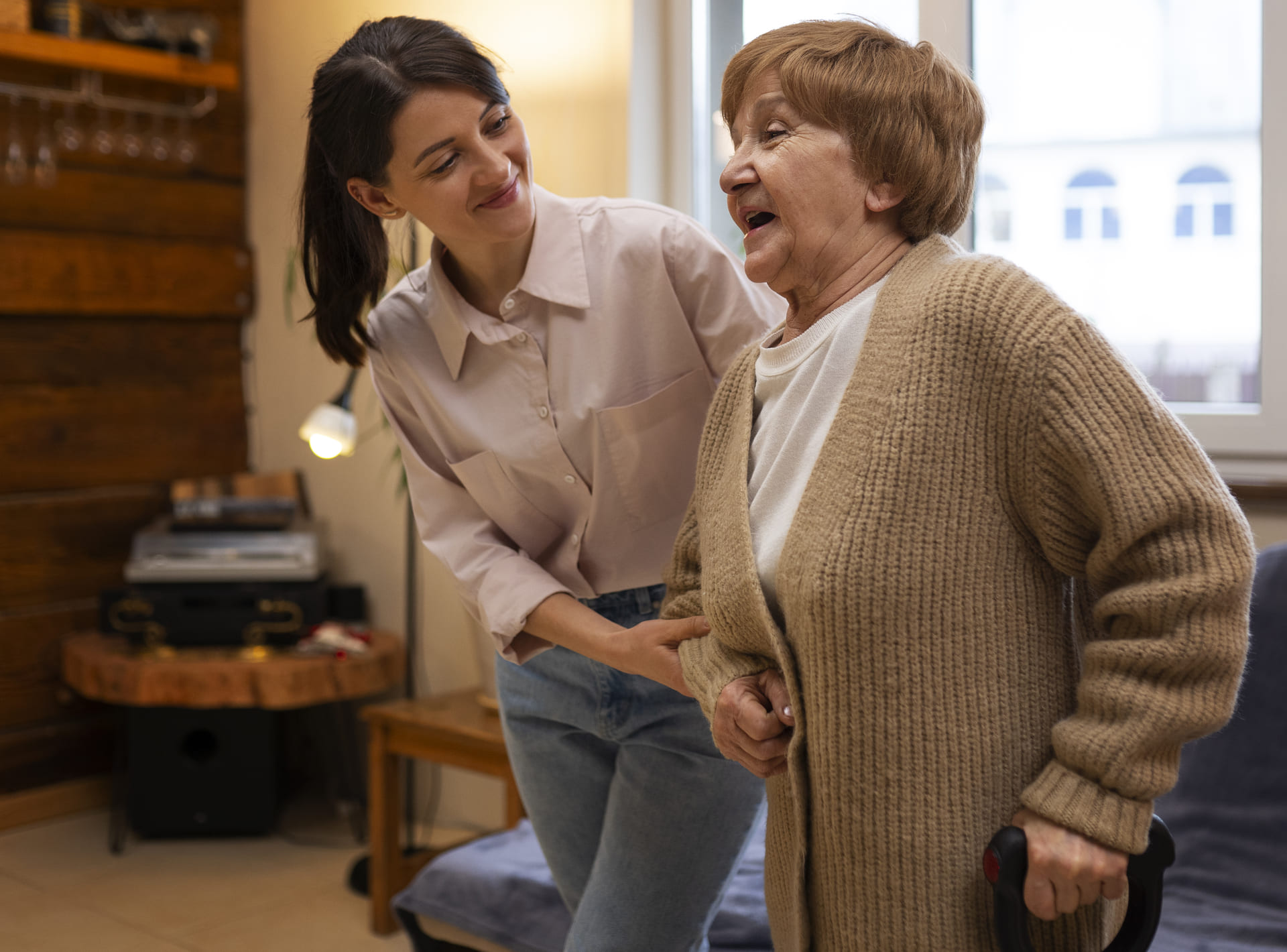 Idoso sorrindo ao conversar com cuidadora em casa de repouso acolhedora